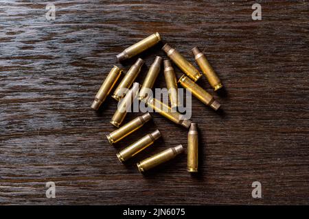 Eine Nahaufnahme leerer Geschosshüllen auf einem dunklen Holztisch Stockfoto