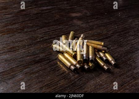 Eine Nahaufnahme leerer Geschosshüllen auf einem dunklen Holztisch Stockfoto