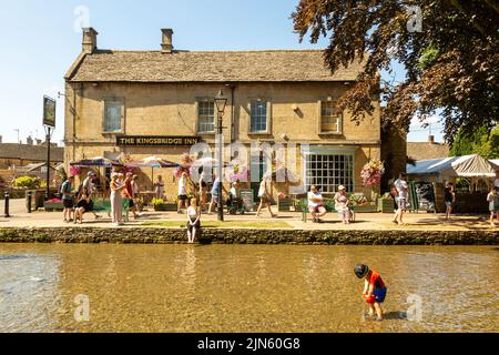 Bourton on the Water, Glocs, Großbritannien. 9. August 2022. Die Menschen sind unterwegs, um die Sonne am River Windrush in Bourton auf dem Wasser, Glocestershire, zu genießen, da die Temperaturen in der kommenden Woche steigen werden. Kredit: Peter Lopeman/Alamy Live Nachrichten Stockfoto