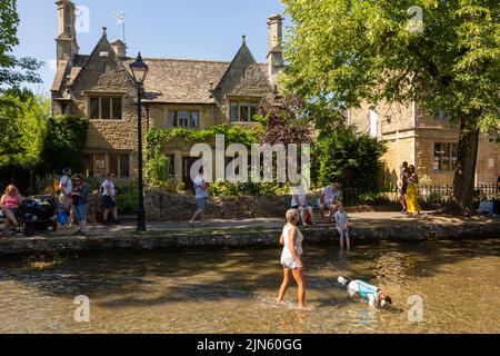 Bourton on the Water, Glocs, Großbritannien. 9. August 2022. Die Menschen sind unterwegs, um die Sonne am River Windrush in Bourton auf dem Wasser, Glocestershire, zu genießen, da die Temperaturen in der kommenden Woche steigen werden. Kredit: Peter Lopeman/Alamy Live Nachrichten Stockfoto