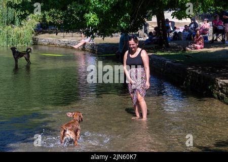 Bourton on the Water, Glocs, Großbritannien. 9. August 2022. Die Menschen sind unterwegs, um die Sonne am River Windrush in Bourton auf dem Wasser, Glocestershire, zu genießen, da die Temperaturen in der kommenden Woche steigen werden. Kredit: Peter Lopeman/Alamy Live Nachrichten Stockfoto