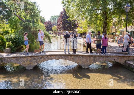 Bourton on the Water, Glocs, Großbritannien. 9. August 2022. Die Menschen sind unterwegs, um die Sonne am River Windrush in Bourton auf dem Wasser, Glocestershire, zu genießen, da die Temperaturen in der kommenden Woche steigen werden. Kredit: Peter Lopeman/Alamy Live Nachrichten Stockfoto