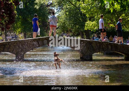 Bourton on the Water, Glocs, Großbritannien. 9. August 2022. Die Menschen sind unterwegs, um die Sonne am River Windrush in Bourton auf dem Wasser, Glocestershire, zu genießen, da die Temperaturen in der kommenden Woche steigen werden. Kredit: Peter Lopeman/Alamy Live Nachrichten Stockfoto