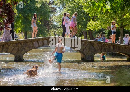 Bourton on the Water, Glocs, Großbritannien. 9. August 2022. Die Menschen sind unterwegs, um die Sonne am River Windrush in Bourton auf dem Wasser, Glocestershire, zu genießen, da die Temperaturen in der kommenden Woche steigen werden. Kredit: Peter Lopeman/Alamy Live Nachrichten Stockfoto