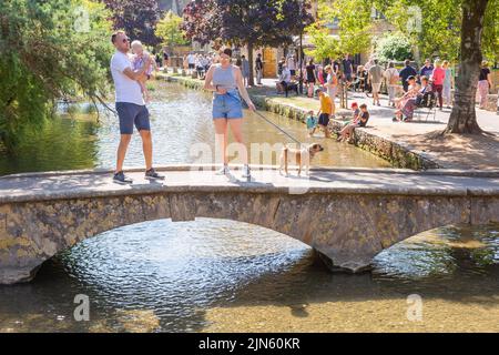 Bourton on the Water, Glocs, Großbritannien. 9. August 2022. Die Menschen sind unterwegs, um die Sonne am River Windrush in Bourton auf dem Wasser, Glocestershire, zu genießen, da die Temperaturen in der kommenden Woche steigen werden. Kredit: Peter Lopeman/Alamy Live Nachrichten Stockfoto