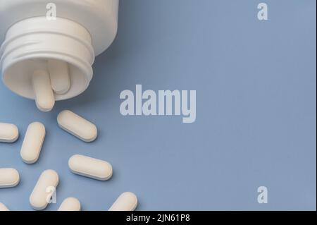 Vitamine Tabletten Ergänzungen Medizin kommt aus der Flasche auf blauem Hintergrund. Mit Platz für Wortwahl. Stockfoto