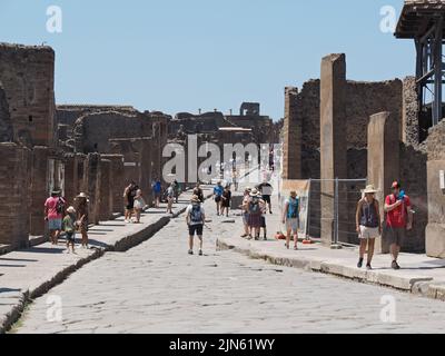 Straße in der Ausgrabungsstätte Pompeji mit vielen Touristen, die die römische Stadt besuchen. Pompei, Kampanien, Italien Stockfoto