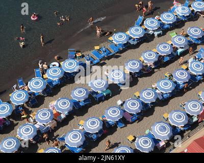 Viele blaue Sonnenschirme am schmalen Strand von Sorrento, Kampanien, Italien. Stockfoto