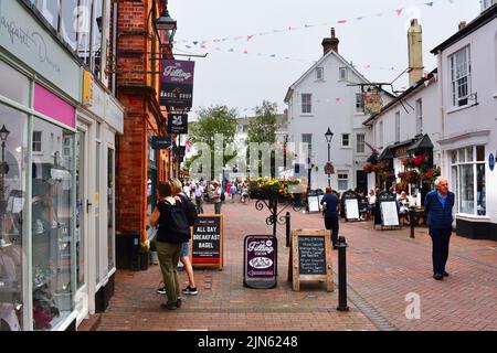 Eine geschäftige Straßenszene mit Urlaubern im Zentrum von Sidmouth. Besucher sitzen vor dem Anchor Inn, beliebt für Mittag- und Abendessen. Stockfoto