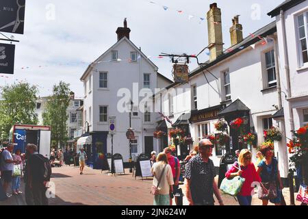 Eine geschäftige Straßenszene mit Urlaubern im Zentrum von Sidmouth. Besucher sitzen vor dem Anchor Inn, beliebt für Mittag- und Abendessen. Stockfoto