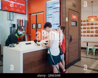 Die Frau bestellt im Fastfood-Restaurant Burger King über das elektronische Touchscreen-Menü eine Mahlzeit Stockfoto