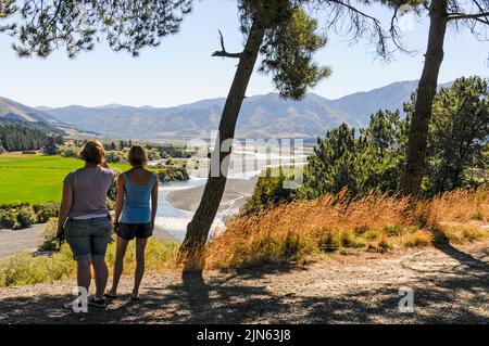 Zwei junge Besucher bewundern den Waiau Fluss in der Nähe des Hanmer Hot Springs & Spa Resorts in den Canterbury Ebenen auf der Südinsel in Neuseeland Stockfoto