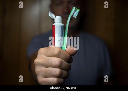 Ein Mann mit einer Zahnbürste und einer Tube Zahnpasta in der Hand Stockfoto