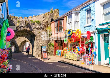 Farbenfrohe Schaufel- und Spatengeschäfte neben der historischen Stadtmauer in Five Arches in der St George's Street, Tenby, Pembrokeshire, Wales, Großbritannien Stockfoto