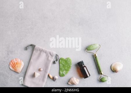 Jade Gesichtswalze, Gua Sha Massagestein, Gesichtsöl und natürliche Muschelschalen. Beauty-Behandlung, Wellness, Hautpflege-Konzept. Stockfoto