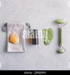 Quadratische Kosmetologie flach Lay mit natürlichen Gesicht massieren Werkzeuge. Massagegeräte mit Gesichtsöl und Gua Sha Jade-Steinen. Selbstpflege- und Hautpflegekonzept. Stockfoto
