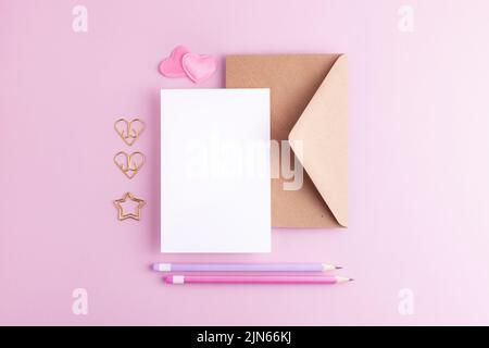 Valentinstag Gruß Mock up mit unbeschriftete Karte, Umschlag, Herzen und Bleistifte. Kreatives Knollenlegen flach mit leerem Raum. Stockfoto