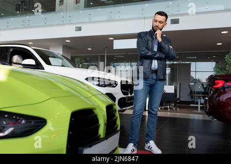 Ein junger Mann wählt sich in einem Autohaus einen Sportwagen aus Stockfoto