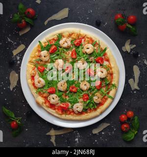 Italienische Pizza mit hausgemachter Tomatensauce, gerösteten Scrimps, Rucola und Kirschtomaten Stockfoto