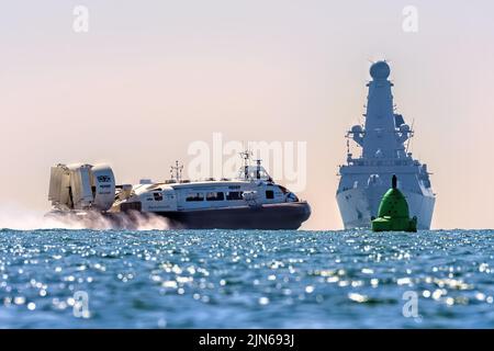 Der Hovercraft Solent Flyer fährt vor dem Typ 45 Zerstörer HMS Duncan vorbei und macht sich am 2022. Mai in Portsmouth Harbour auf den Weg. Stockfoto