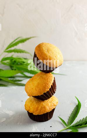 Drei Muffins aus Marihuana-Cupcake mit Cannabisblättern. Glutenfrei. Alternative Süßwaren-Konzept. Vertikale Ausrichtung. Selektiver Fokus. Stockfoto