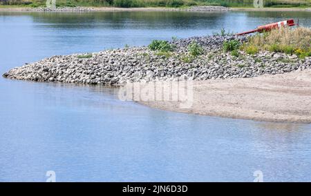 Darchau, Deutschland. 09. August 2022. Die normalerweise überflutete Steinmole an den Ufern der Elbe ist trocken. Die Fährverbindung zwischen Darchau und Neu Darchau musste wegen zu niedrigem Wasserstand eingestellt werden. Mehr als 1.500 Menschen nutzen die Fähre in Neuhaus im Durchschnitt täglich. Aufgrund der Schließung der nahegelegenen alternativen Brücke müssen Pendler derzeit lange Umwege zurückgelegt werden. Quelle: Jens Büttner/dpa/Alamy Live News Stockfoto