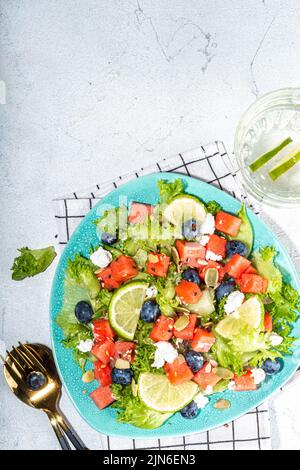 Sommer-Wassermelonensalat. Frischer roher grüner Salat mit Salat, Rucola, Wassermelonenscheiben, Heidelbeere, Feta-Käse und Honig Stockfoto