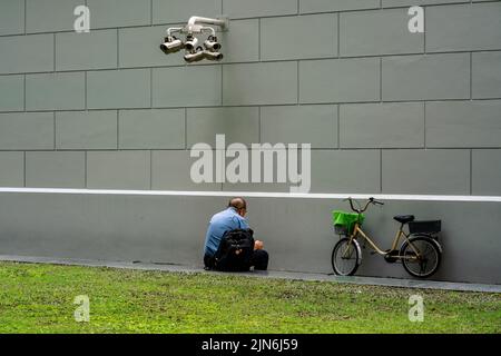 Ein Mann ruht vor der MRT-Station des Raffles Place in Singapur. Horizontale Aufnahme. Stockfoto