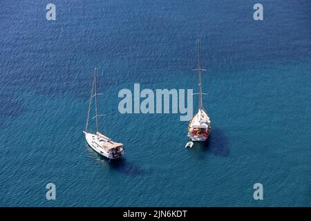 Luftaufnahme zu Yachten mit abgesenkten Segeln auf blauer Meeresoberfläche. Zwei Segelboote liegen vor Anker, Hintergrund für Reisen und Urlaub Stockfoto