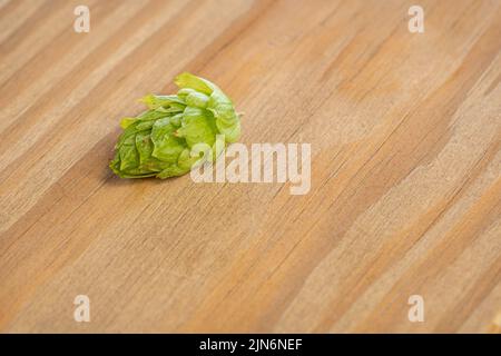 Detail von Hopfenblättern des Kegels, die auf einem Holzbrett liegen. Stockfoto