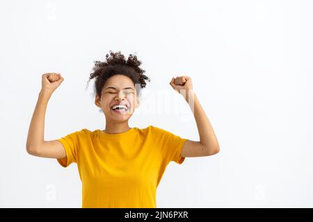 Lustige junge afroamerikanische Frau, die den Sieg auf weißem Hintergrund feiert Stockfoto