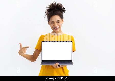Junge Frau mit Laptop auf weißem Hintergrund schöne Frau zeigt ihren Finger auf leeren Laptop-Bildschirm Stockfoto
