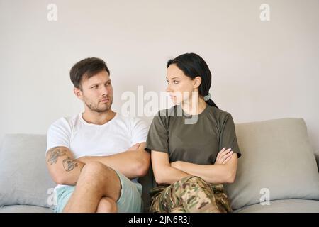 Junges Paar, das in geschlossenen Posen auf dem Sofa sitzt Stockfoto