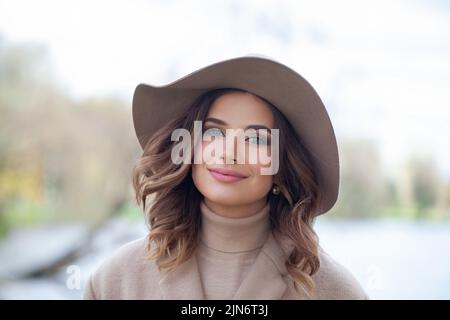 Fröhliche hübsche Frau mit stilvollem Hut im Park Stockfoto