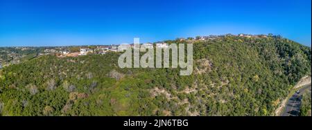 Austin. Texas - Panoramablick auf Villen und Villen auf einem Hang gegen den klaren blauen Himmel. Unten rechts befindet sich eine Autobahn Stockfoto