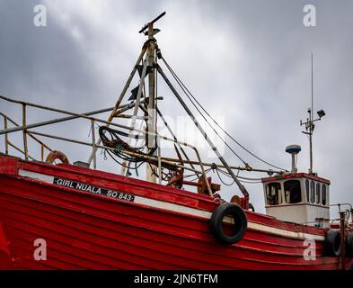 Greencastle, Irland - 9. Juli 2022: Farbenfrohe rote Fischerboot-Trawler im geschützten Hafen und Hafen von Greencastle Stockfoto