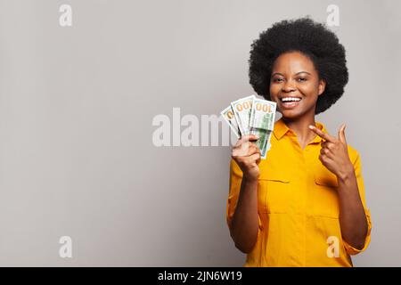 Frau gewinnt Geld. Glückliche Frau mit überraschendem Ausdruck, die einen Haufen hundert-Dollar-Banknoten in der Hand hält. Finanz- und Personalkonzept Stockfoto