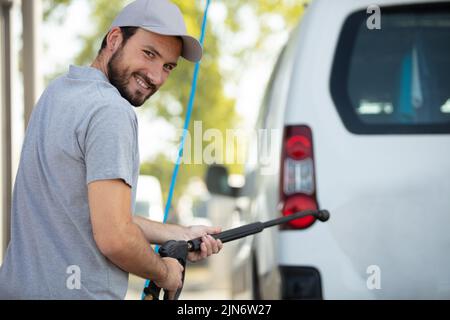 Mann wäscht seinen Van mit einem Hochdruckreiniger Stockfoto