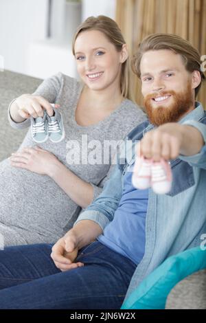 Crop Paar mit winzigen Schuhen auf den Händen Stockfoto