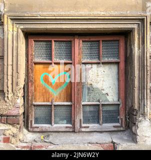 Herzgraffiti auf dem alten Hausfenster Stockfoto