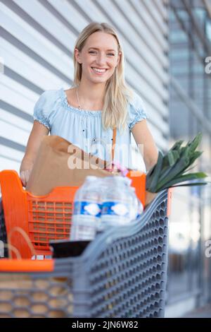 Junge attraktive Frau, die einen Einkaufswagen schiebt Stockfoto