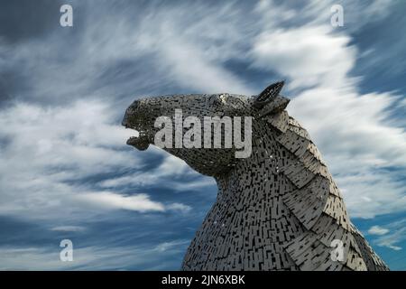 Falkirk, Vereinigtes Königreich - 20. Juni 2022: Eine der Kelpies-Pferdekopfskulpturen mit einem ausdrucksstarken, langbelichteten Himmel dahinter Stockfoto