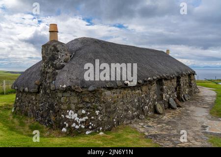 Kilmuir, Großbritannien - 1. Juli 2022: Nahaufnahme eines typischen Crofter-Cottage mit dicken Steinmauern und einem Reetdach Stockfoto