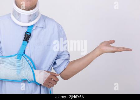 Porträt eines asiatischen Mannes mit gebrochenem Arm und Hals zeigt leeren Raum isoliert auf weißem Hintergrund kopieren Raum für Text Stockfoto