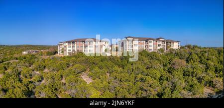 Austin, Texas – komplexe Apartmentgebäude in der Nähe der Klippe mit Panoramablick. Wohngebäude auf einem Hang mit Bäumen gegen den klaren Berg Stockfoto