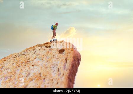Wanderer mit Rucksack auf einer Scheibe Toast bei Sonnenaufgang, Miniaturmenschen Stockfoto