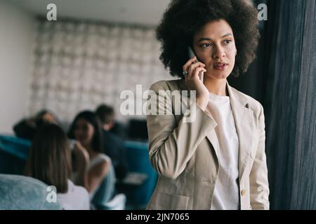 Schöne afrikanische Firmenarbeiter im Gespräch auf Handy Stockfoto