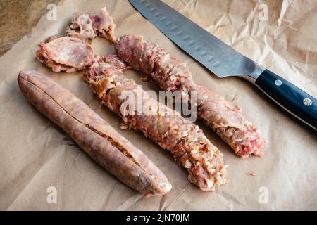 Entfernen der Hülsen von drei irischen Würstchen: Entfernen der Wursthülsen, um zerkonstruierte Knaller und Maische zu machen Stockfoto