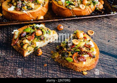 Karamellisierter Brüsseler Sprout-Toast mit Burrata & Bacon: Blick von oben auf geröstetes Brot mit Gemüse, Mozzarella-Käse und Speck Stockfoto