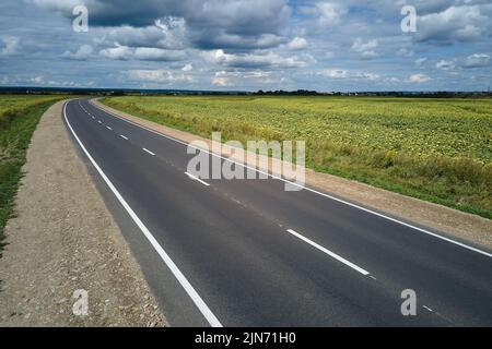 Luftaufnahme einer leeren Intercity-Straße zwischen grünen landwirtschaftlichen Feldern. Draufsicht von der Drohne der Autobahn Stockfoto